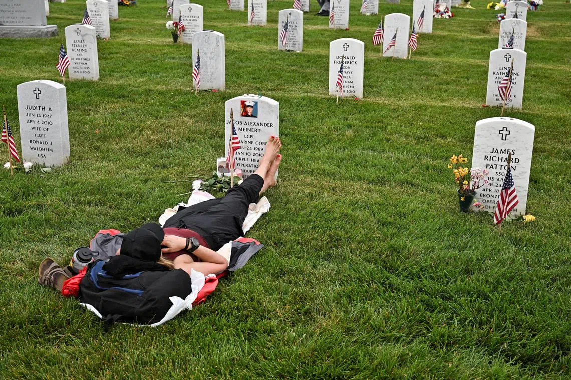 Krista Meinert lying at the grave site of her son Jacob Meinert in Section 60 at Arlington National Cemetery on Memorial Day in Washington on May 29, 2023. 