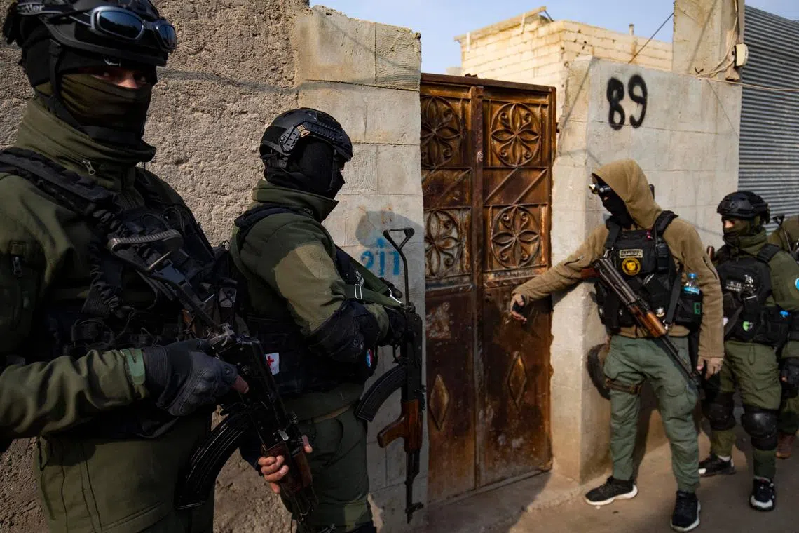 Syrian Kurdish Asayish security forces knock on the door of a house during a raid against suspected Islamic State fighters in Raqa, the militant group's former defacto capital in Syria, on Jan 29, 2023. 