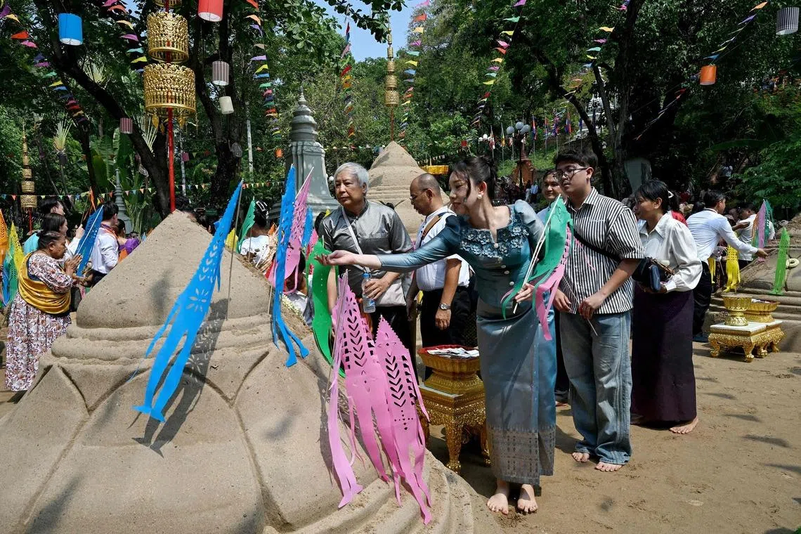 TOPSHOT - People throw sand on sand stupas as they pray during celebrations for the Khmer New Year, known as Nokor Sankranta, in Phnom Penh on April 15, 2026. (Photo by TANG CHHIN Sothy / AFP)