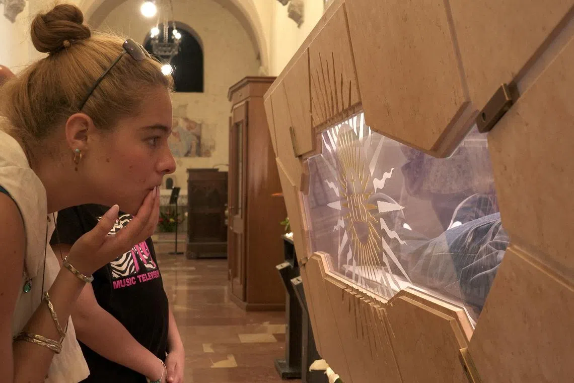 A woman looking at the tomb of Carlo Acutis, who died of leukemia in 2006 at the age of 15, in the Church of Santa Maria Maggiore in Assisi, Italy on May 26, 2024. Pope Francis has cleared the way for Acutis to be recognized as the first saint of the millennial generation.