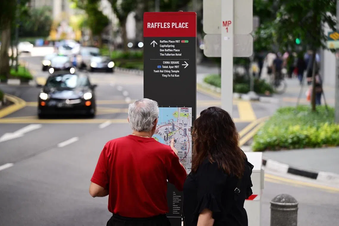 Pedestrian finding their way with the Street-Level Way finding system located at the junction between Chulia Street and Phillip Street. 

 ST PHOTO: AZMI ATHNI