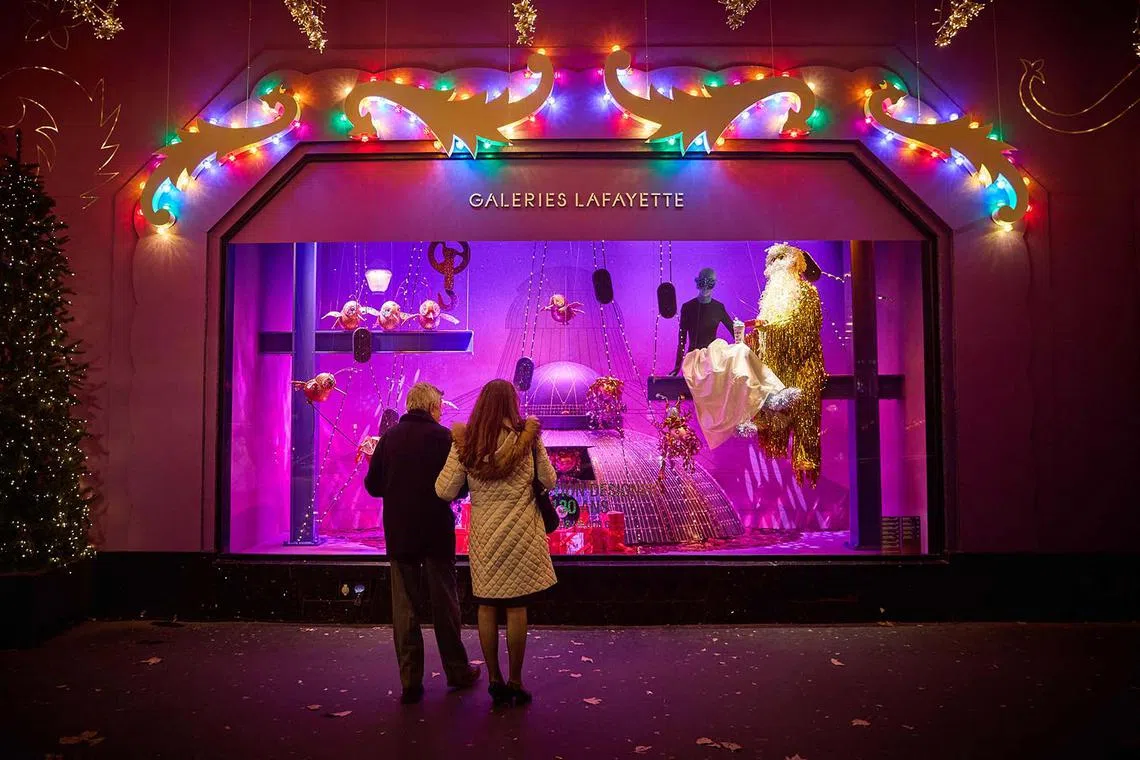 Members of the public looking at one of the windows outside the Galeries Lafayette Paris Haussmann decorated with Christmas lights, as the department store celebrates it's 130th Christmas, in central Paris, on Nov 25, 2024. 