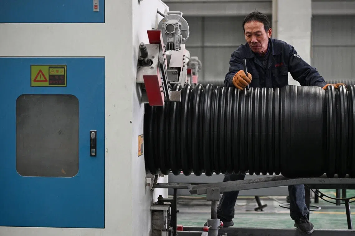 An employee works on the production line of polyethylene pipes at a factory in Suqian, in eastern China's Jiangsu province, on Oct 21.
