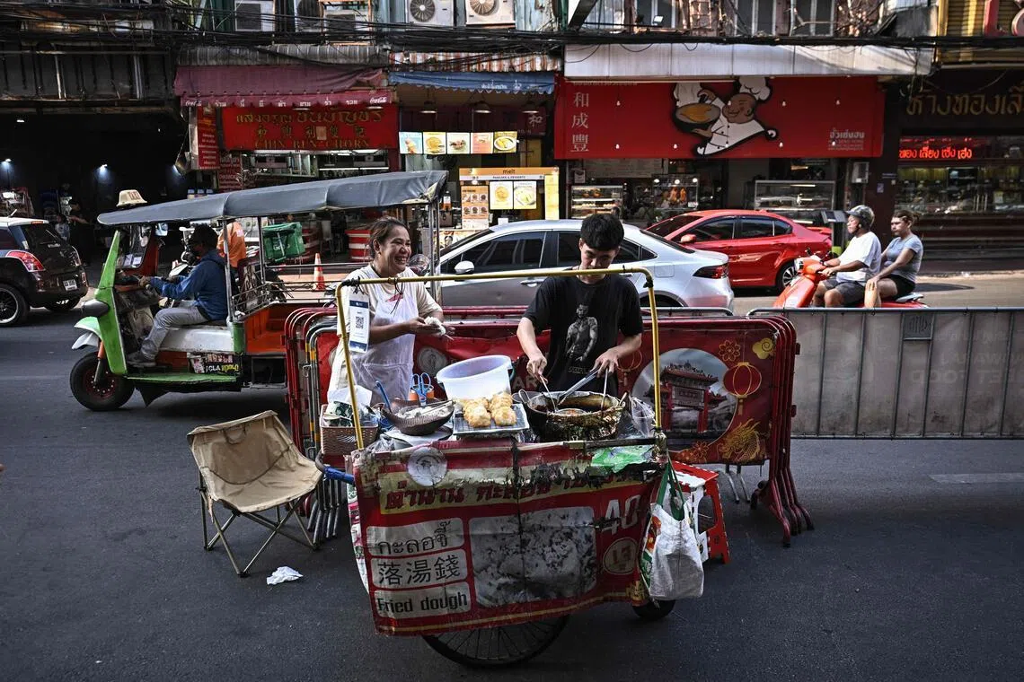 Street food vendor Looknam Sinwirakit (left) prepares fried glutinous rice cakes from a cart in Chinatown in Bangkok on April 29. 
