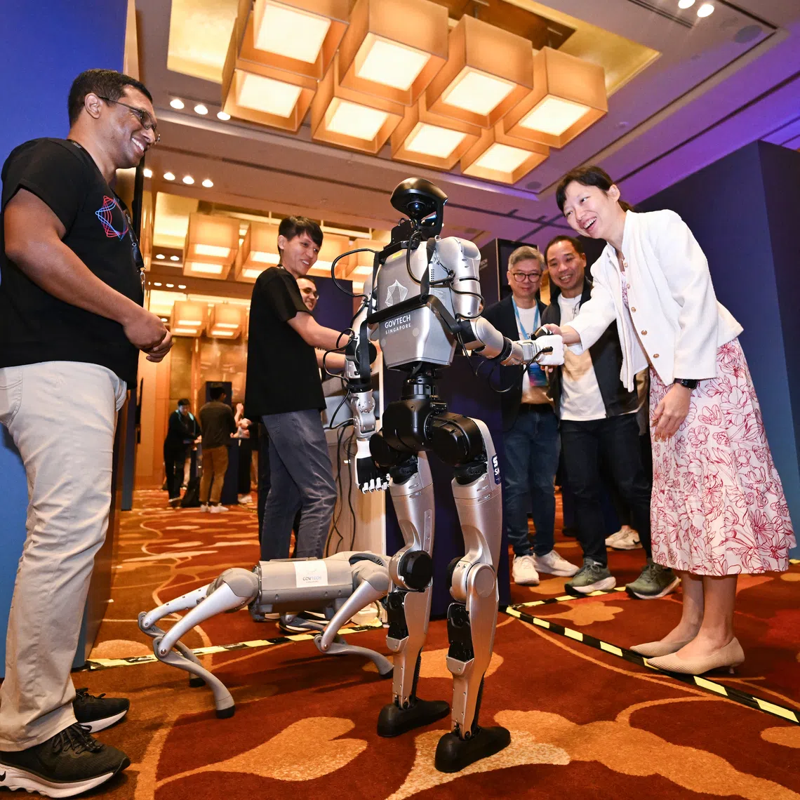 Minister of State for Digital Development and Information Jasmin Lau (right) interacting with a humanoid robot during GovTech Innovation Day 2025 at Marina Bay Sands Expo & Convention Centre on Nov 13.