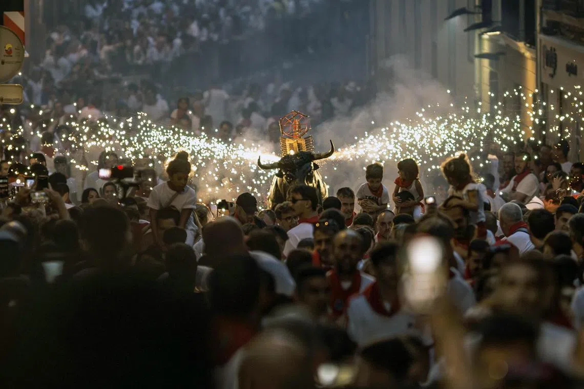 People attending the traditional 'Bull of Fire' parade during the San Fermin festival in Pamplona, northern Spain on 08 July 2023. Pamplona's Running of the Bulls, known locally as Sanfermines, is held annually from 06 to 14 July in commemoration of the city's patron saint. Visitors from all over the world attend the fiesta.  