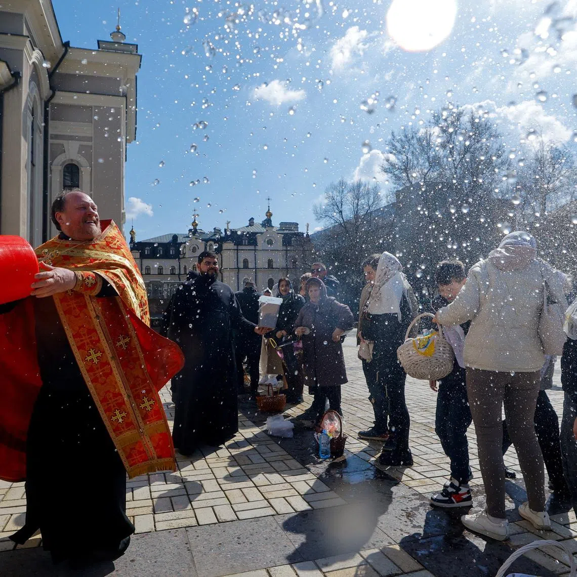 A priest sprays holy water on parishioners outside a cathedral during Orthodox Easter celebrations amid the Russia-Ukraine conflict in Donetsk, a Russian-controlled city of Ukraine, April 12, 2026. REUTERS/Alexander Ermochenko