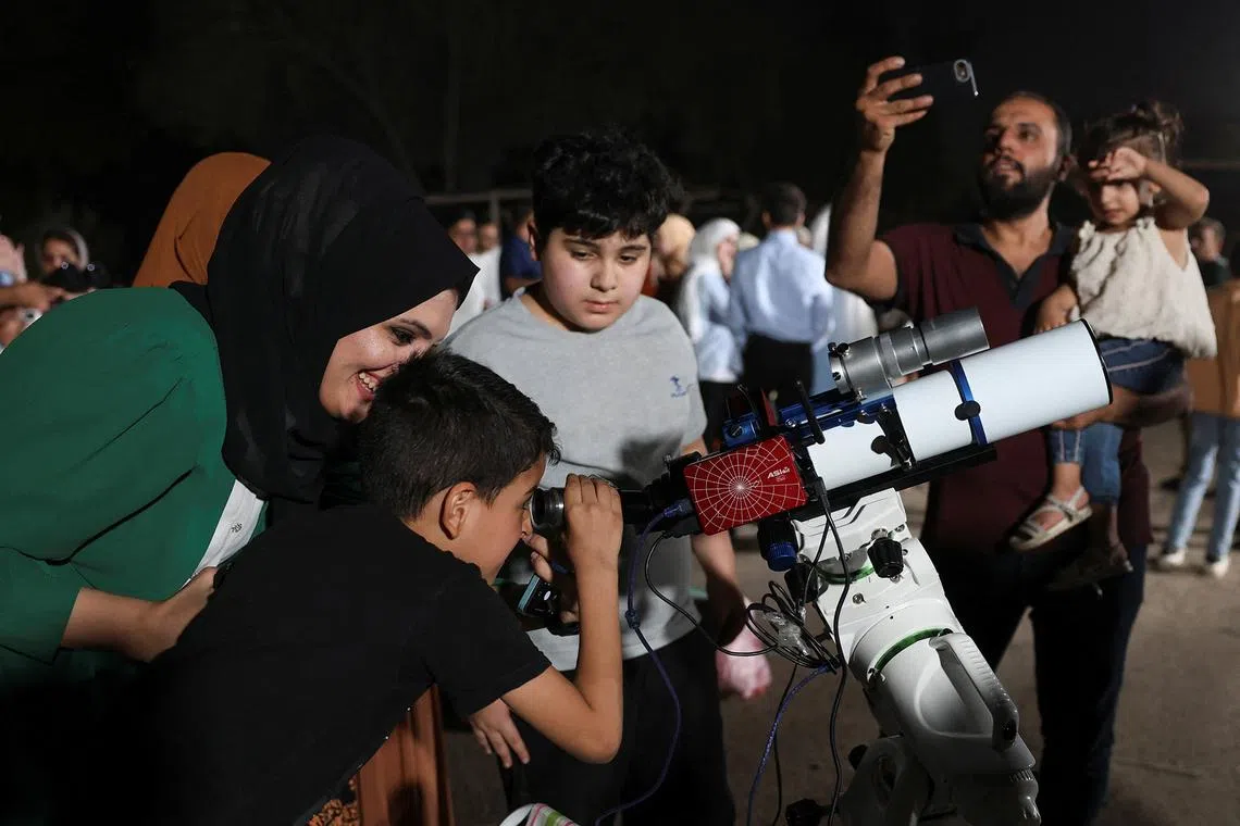 A child uses a telescope to observe the blood moon during a total lunar eclipse at a public event in Baghdad, Iraq, on Sept 7, 2025. 