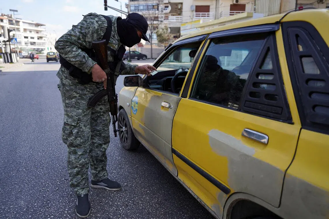 FILE PHOTO: A member of the Syrian security forces checks an ID of a person, after hundreds were killed in some of the deadliest violence in 13 years of civil war, pitting loyalists of deposed President Bashar al-Assad against the country's new Islamist rulers in Latakia, Syria March 9, 2025. REUTERS/Karam al-Masri/File Photo