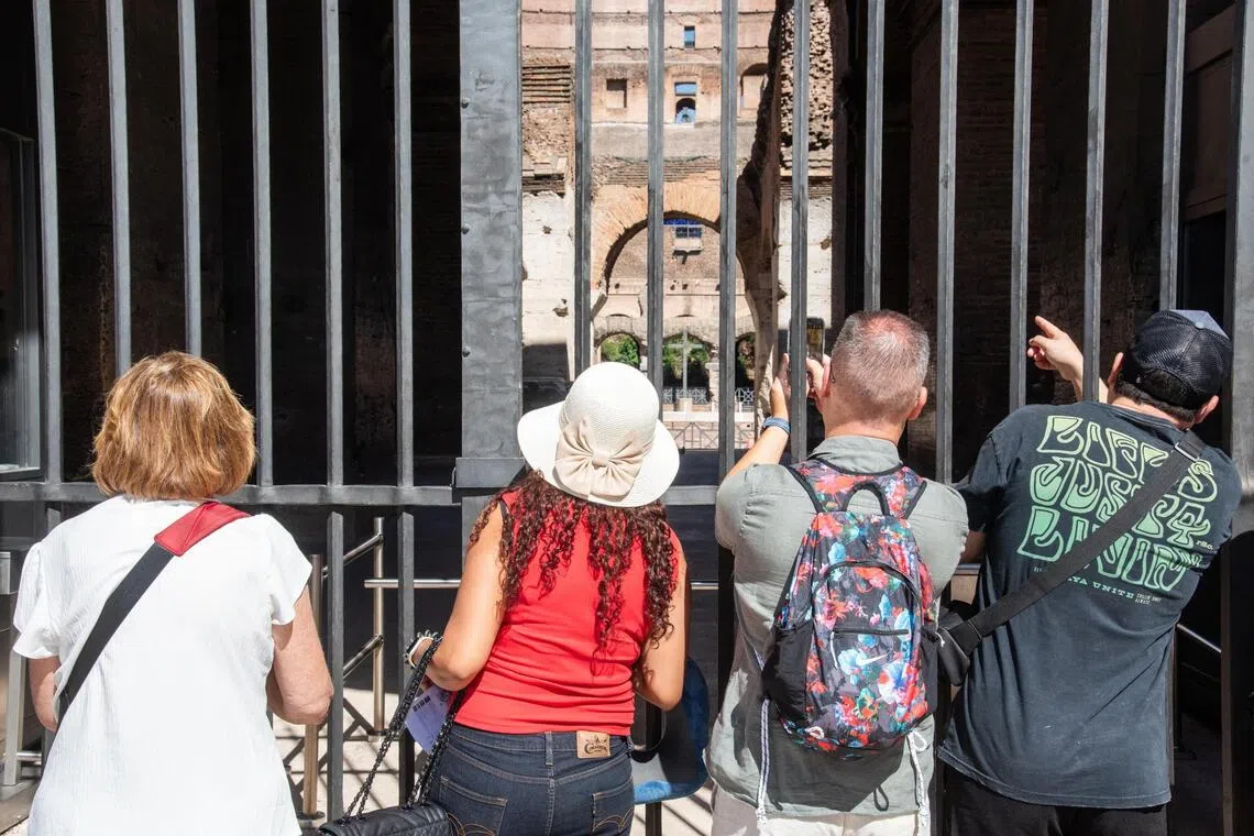Visitors looking through a gate at the Colosseum in Rome, Italy, on Sept 23, after its closure due to the death of 22-year-old technician Andrea Moretti.