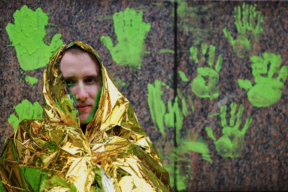 An activist from "Letzte Generation" (Last Generation) sitting in front of a wall of the Hotel Adlon, the venue for the World LNG Summit, after green paint was used to make hand impressions on the wall, in Berlin, Germany, Dec 10, 2024. 