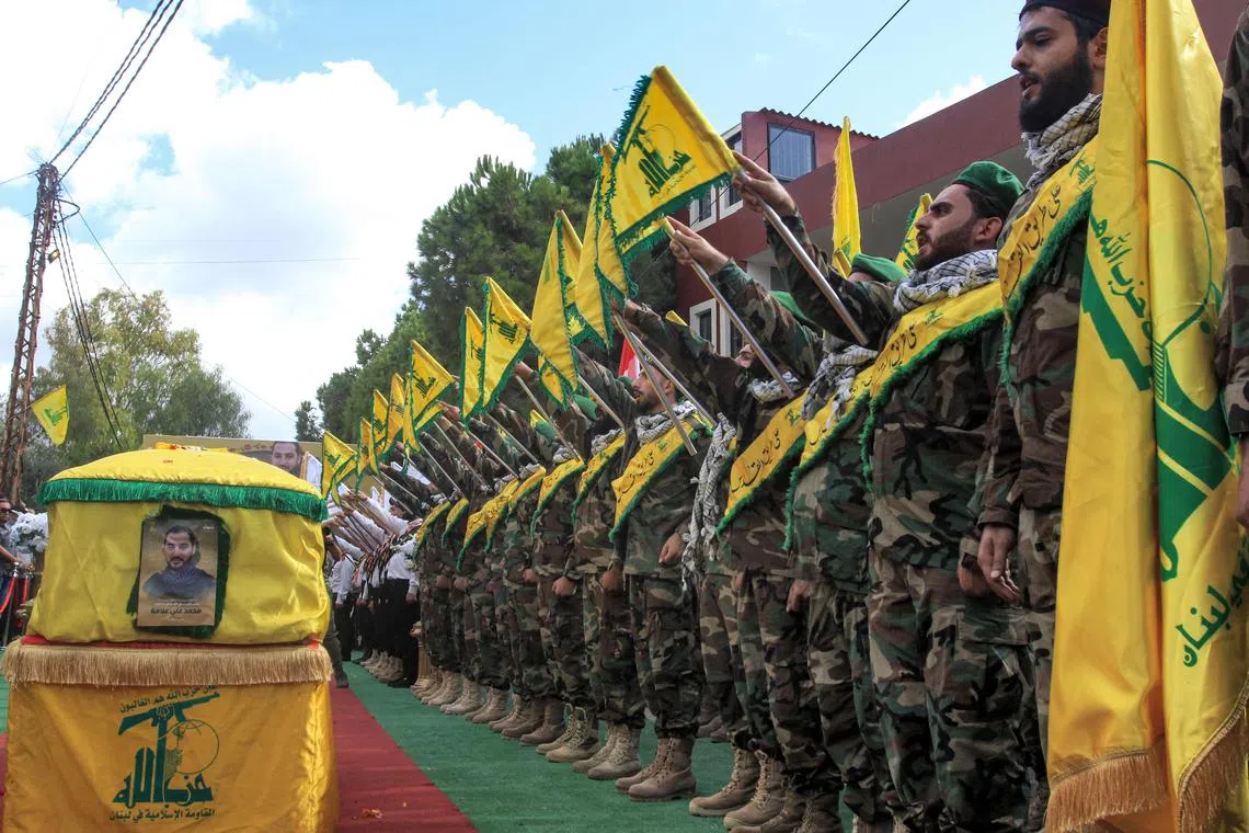 Members of the Lebanese Shi'ite Movement Hezbollah salute during the funeral of a comrade who was killed the previous day by the explosion of a communication device in Adloun, south of Tyre, in southern Lebanon, on Sept 19, 2024. 