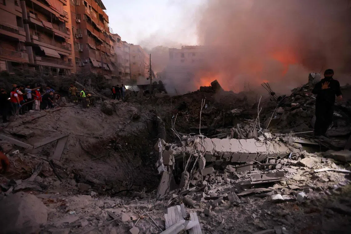 Smoke rises from the smouldering rubble as people gather at the scene of Israeli air strikes in the Haret Hreik neighbourhood of Beirut's southern suburbs, on Sept 27.