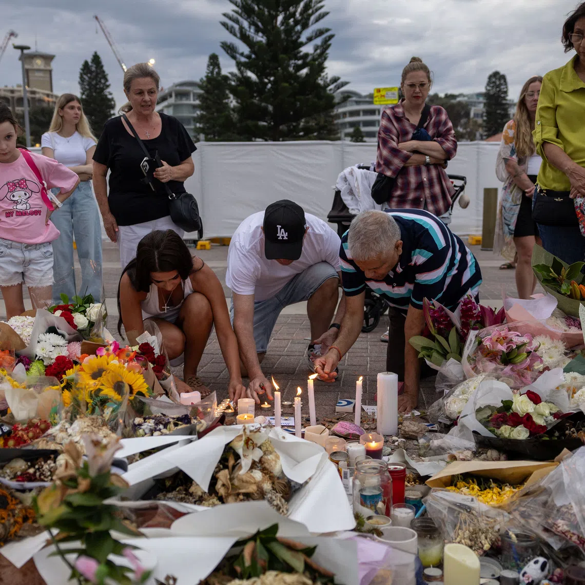 People light candles among the floral tributes for victims and survivors of a deadly mass shooting during a Jewish Hanukkah celebration at Bondi Beach on December 14, in Sydney, Australia, December 21, 2025. REUTERS/Eloisa Lopez