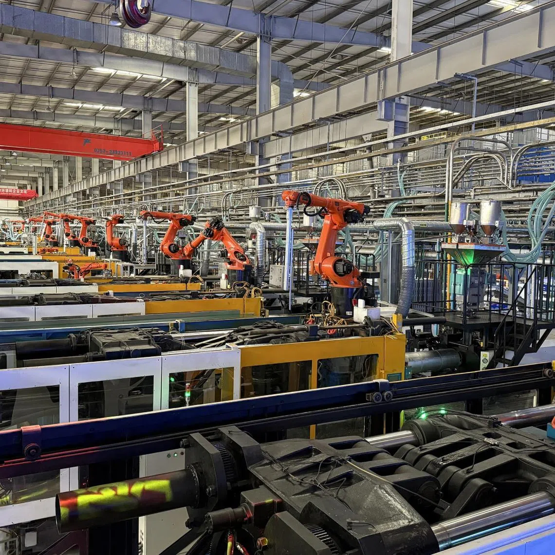 Robotic arms lift freshly-pressed plastic parts out of hot metal moulds and onto a conveyor belt at Midea's air-conditioner factory in Guangzhou.