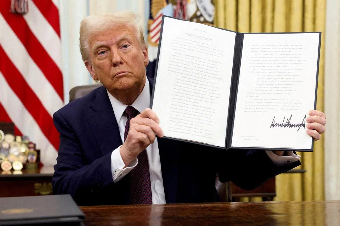 US President Donald Trump holds a signed executive order on cryptocurrencies, in the Oval Office of the White House.