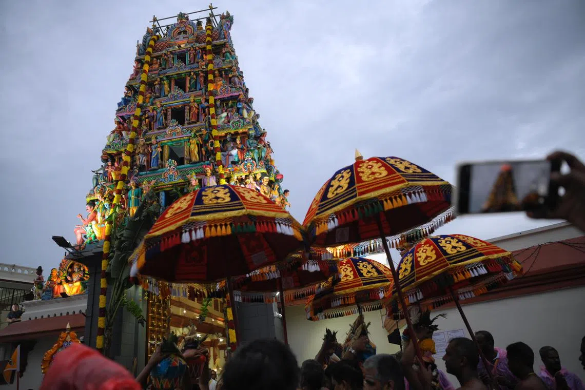 Priests carry vessels of blessed water during the consecration ceremony of Sri Mariamman Temple on Sunday.