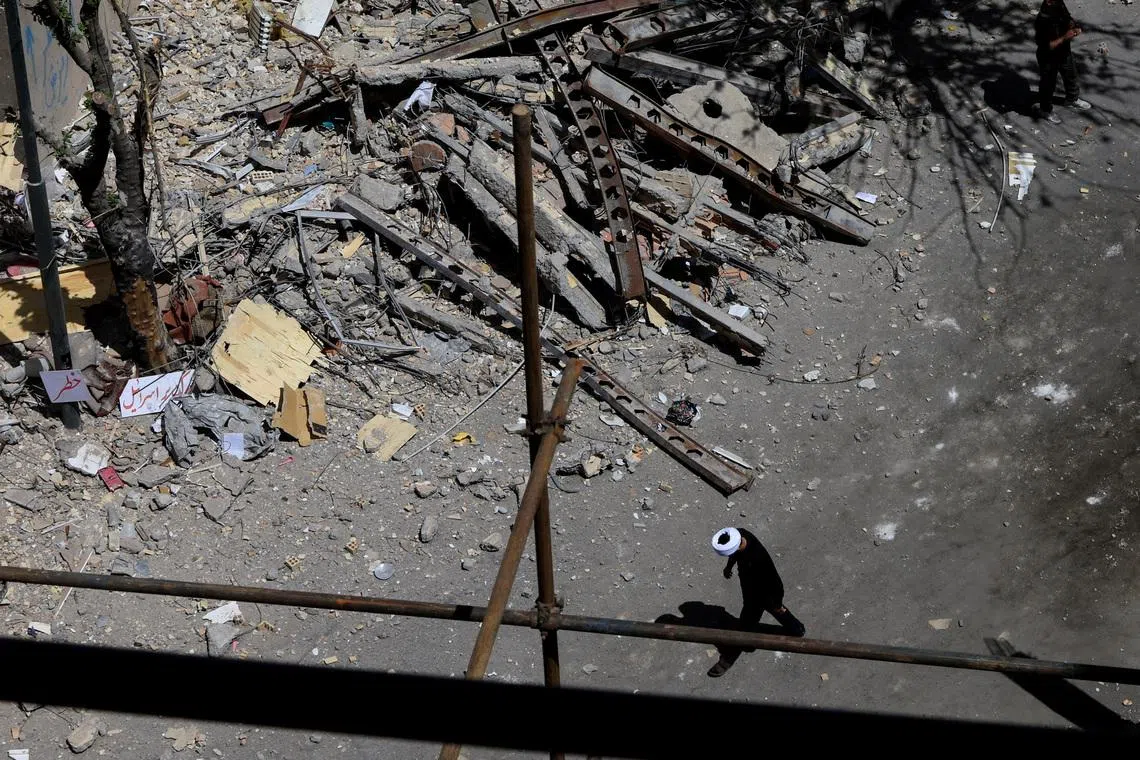 A cleric walks near a residential building damaged by a strike on March 4, in Tehran, Iran, April 14, 2026. REUTERS/Thaier Al Sudani