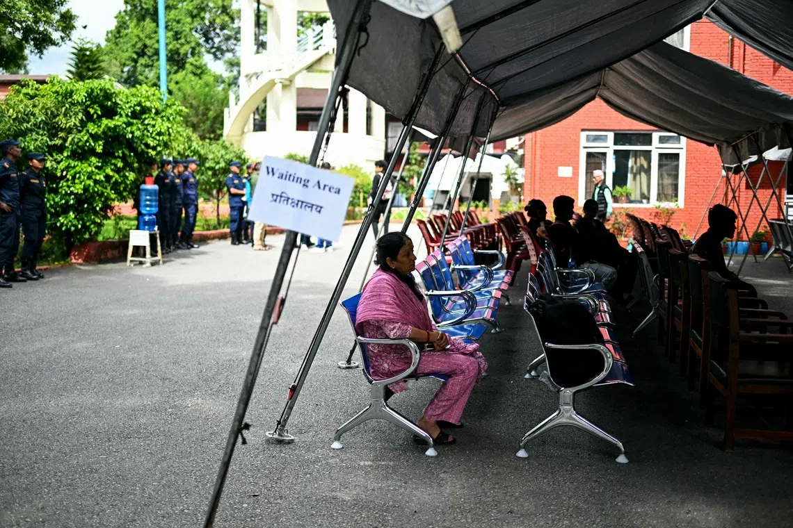 Family members wait to register their information with police personnel to give blood samples for DNA testing to help identify their missing relatives after flash floods.