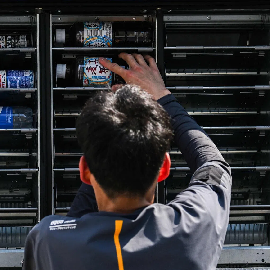 An employee stocks an empty vending machine in Tokyo on July 22.