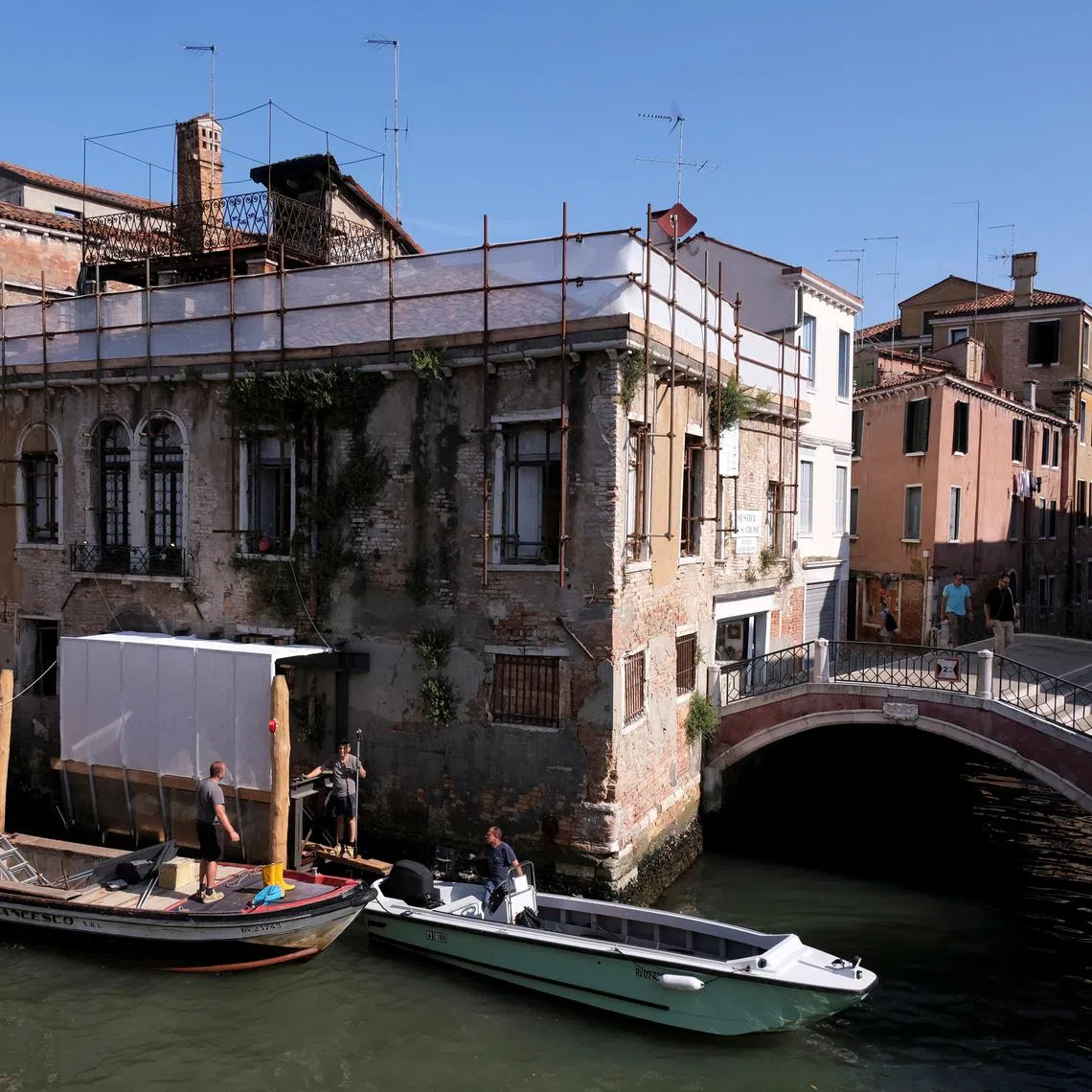 People work at the beginning of the restoration process of Banksy's 'Migrant Child', the mural depicting a migrant child wearing a lifejacket and holding a pink flare in Venice, Italy, June 17, 2025. The mural appeared on San Pantalon palace in 2019 and it will be restored by Ifis art. REUTERS/Manuel Silvestri