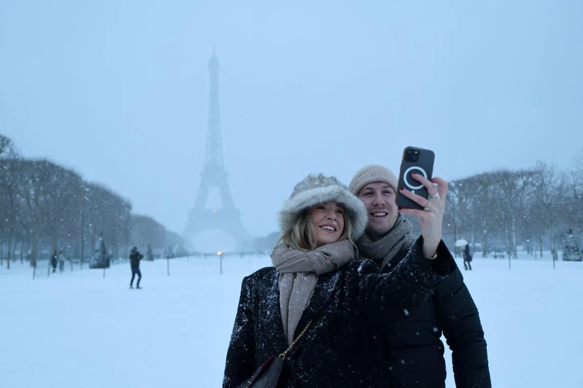 A couple takes a selfie in front of the Eiffel Tower in Paris.