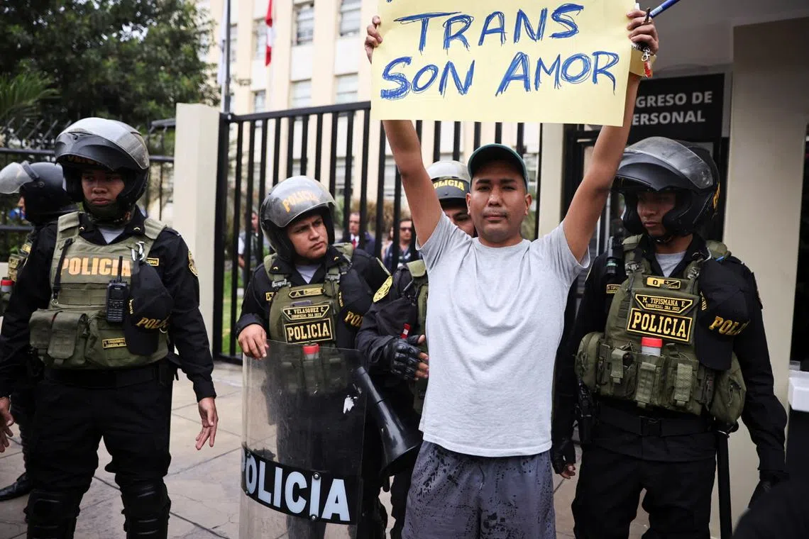FILE PHOTO: A protester carries a sign while police stand guard in a protest by the LGBTQI community against a new government decree listing transsexualism as a \"mental disorder\", in front of the Ministry of Health, in Lima, Peru May 17, 2024. REUTERS/Sebastian Castaneda/File Photo