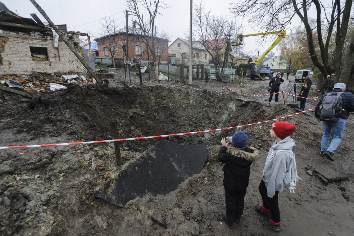 Locals look at a crater left after a recent rocket attack in the village of Solonka, not far from the Western Ukrainian city of Lviv, Ukraine, on Nov 16, 2022, amid the Russian invasion of Ukraine. 