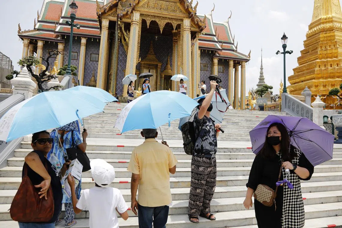 People use umbrellas to shield themselves from the blazing sun during hot weather as they visit the popular tourist spots in Bangkok, Thailand, May 8, 2023. Thai officials issued health warnings to citizens to be aware of heatstroke as temperatures continue to rise.