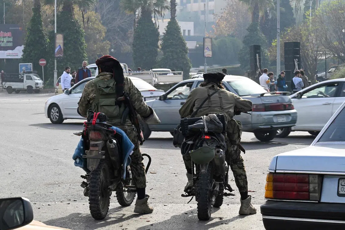 Rebel fighters patrol a street in Damascus on December 10, 2024. Syria's Islamist rebel leader on December 9 began discussions on transferring power, a day after his opposition alliance dramatically unseated president Bashar al-Assad following decades of brutal rule. (Photo by LOUAI BESHARA / AFP)