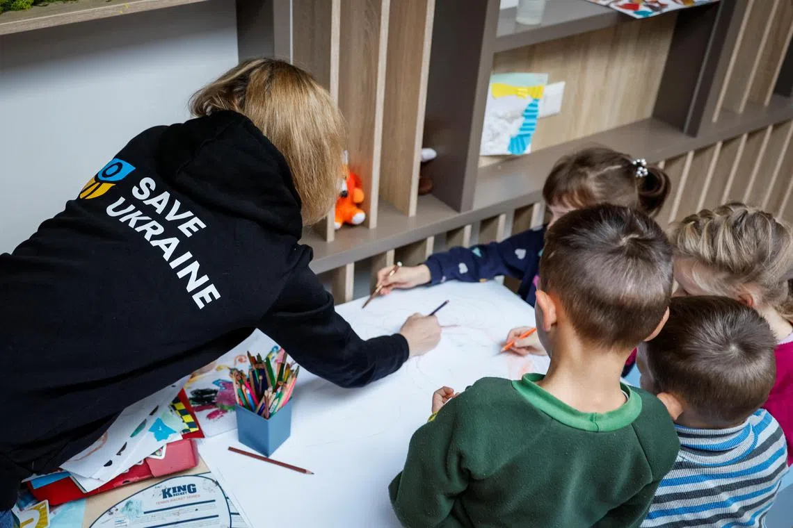 A volunteer of Save Ukraine paints with rescued children, in Kyiv. Ukrainian officials say 20,000 children have been taken from Ukraine to Russia without family or guardians' consent.