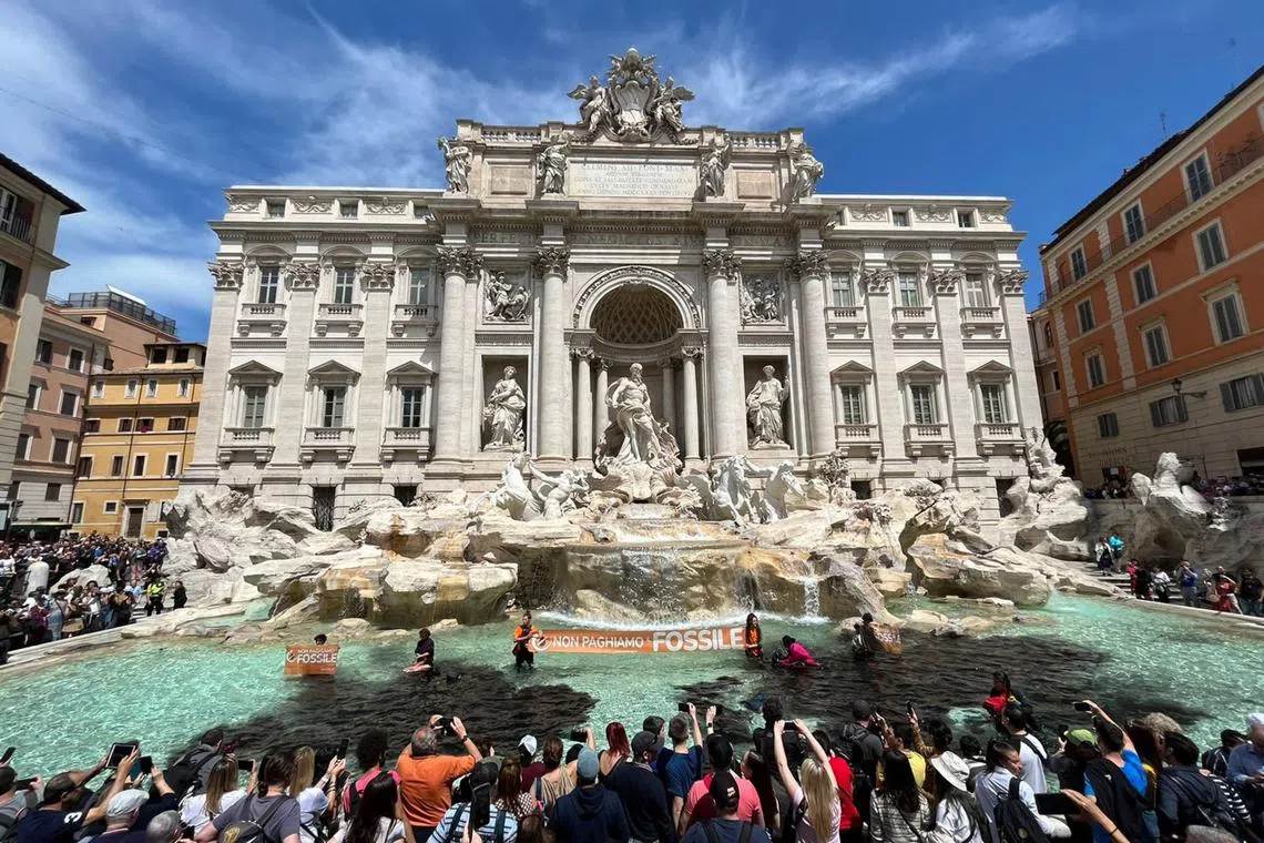 Climate activists from the group Last Generation stand inside the Trevi Fountain in Rome, on May 21, 2023.