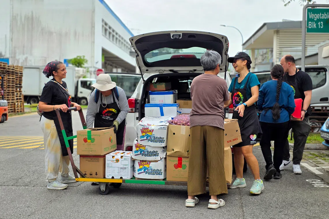 Fridge Restock Community SG (FRC) volunteers loading a car with rescued fruit and vegetables at Pasir Panjang Wholesale Centre.
