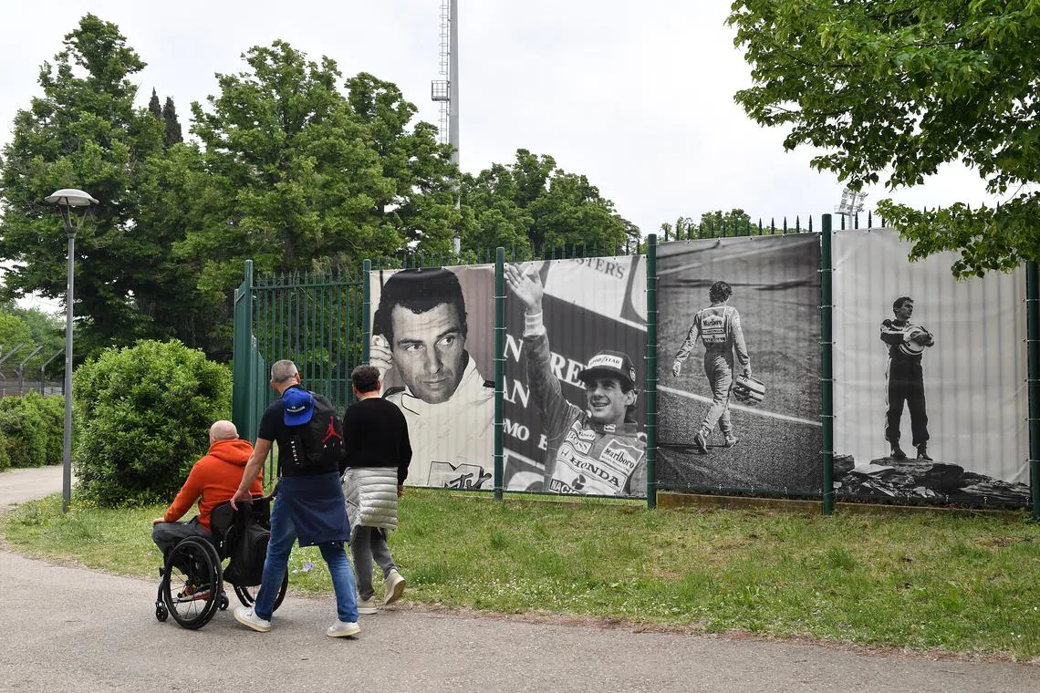 FILE PHOTO: Formula One F1 - 30th Anniversary of Ayrton Senna's death - Autodromo Enzo e Dino Ferrari, Imola, Italy - May 1, 2024 Fans walk past images of Ayrton Senna on the 30th Anniversary of his death REUTERS/Jennifer Lorenzini/File Photo