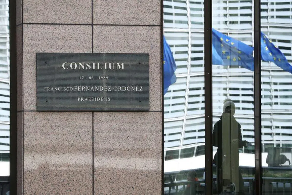 FILE PHOTO: General view of a woman reflecting in a window with EU flags behind at an entrance of the European Council headquarters in Brussels, Belgium March 4, 2020. REUTERS/Yves Herman/File Photo