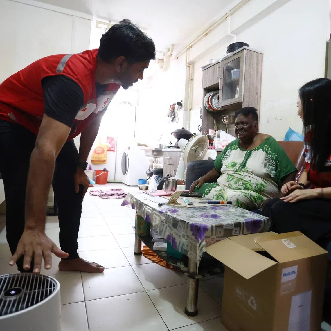 Staff from the Singapore Red Cross showing Anna Mary Raja Letchumi, 80, how to use the air purifier at her home in Woodlands on Sept 9.