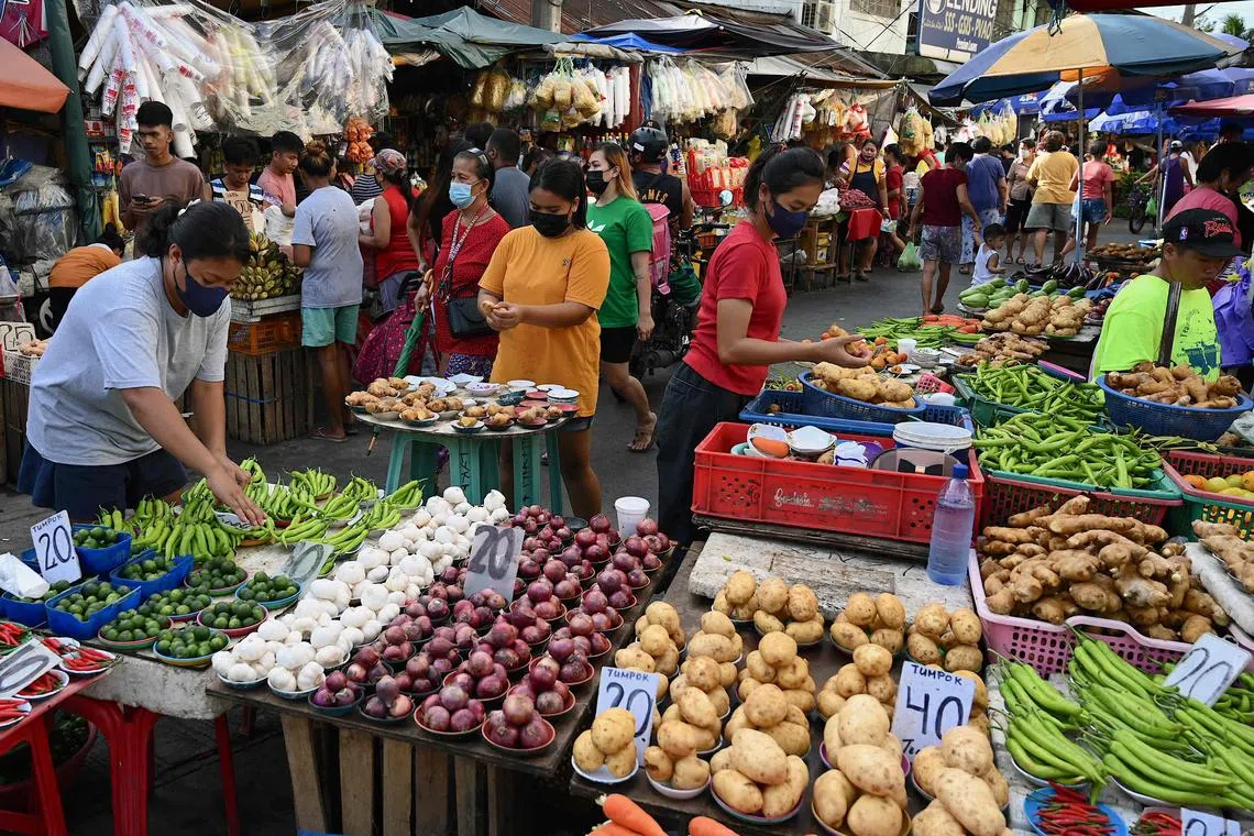 Vendors tend to their stalls as customers browse at a market in Manila on September 21, 2022.