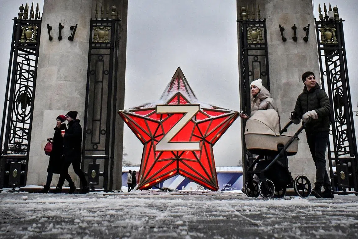 People walk past a New Year decoration Kremlin Star, bearing a Z letter, a tactical insignia of Russian troops in Ukraine, at the Gorky Park in Moscow on Dec 29, 2022. 