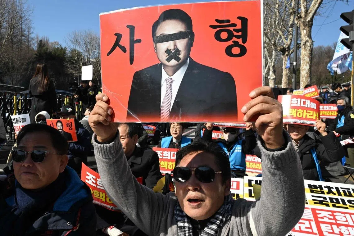 A protester with a placard showing a photo of South Korea's former president Yoon Suk Yeol reading "A death sentence" during a rally near the Seoul Central District Court on Feb 19.