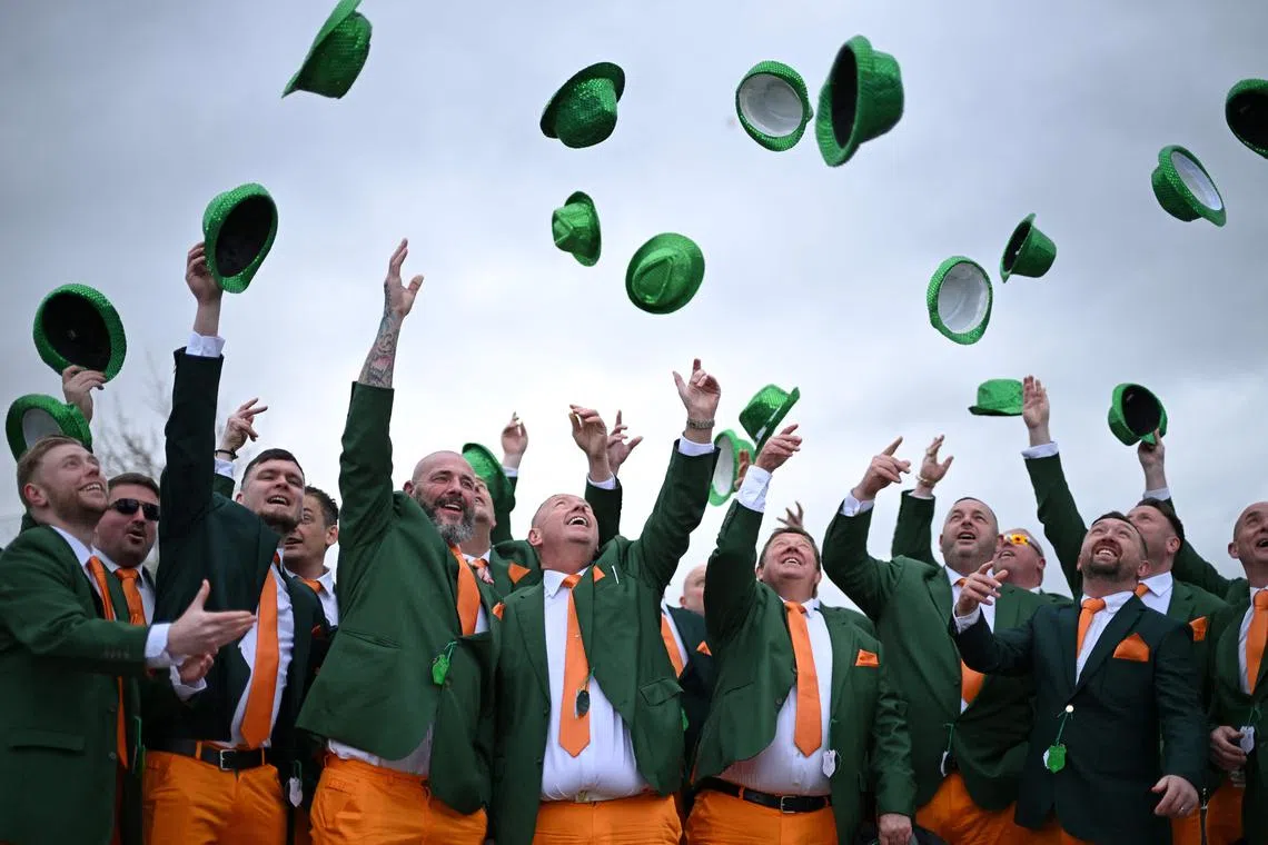 Racegoers dressed in Irish colours hurling their hats into the air as St Patrick's Day is celebrated at the course on the third day of the Cheltenham Festival at Cheltenham Racecourse, in Cheltenham, western England, on Mar 13, 2025. 
