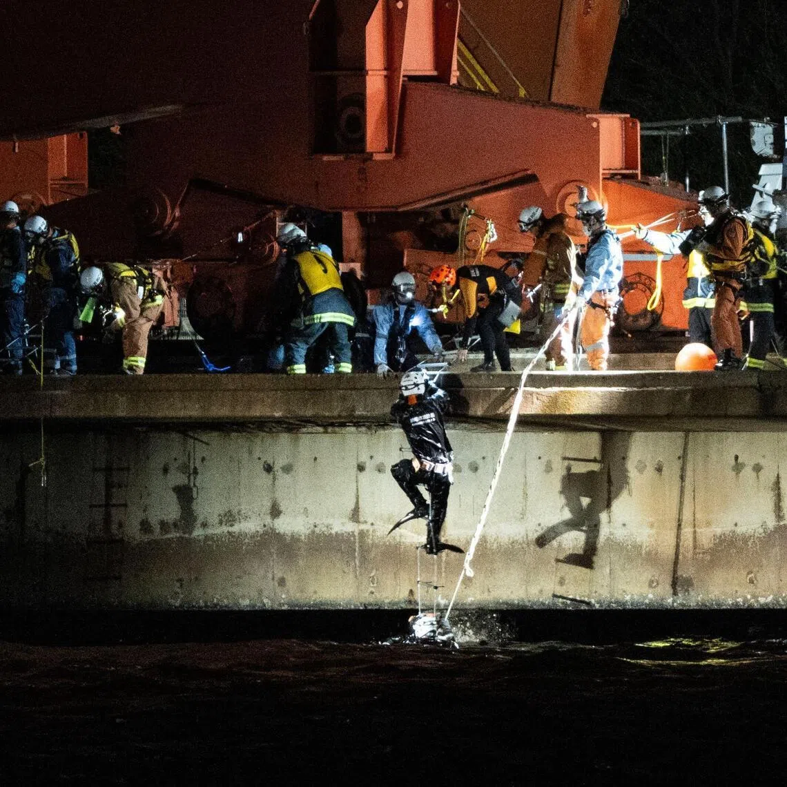 Emergency swimmers climb out of the water at the JFE Steel East Japan Works Keihin District construction site in Kawasaki, Kanagawa prefecture, on April 7.