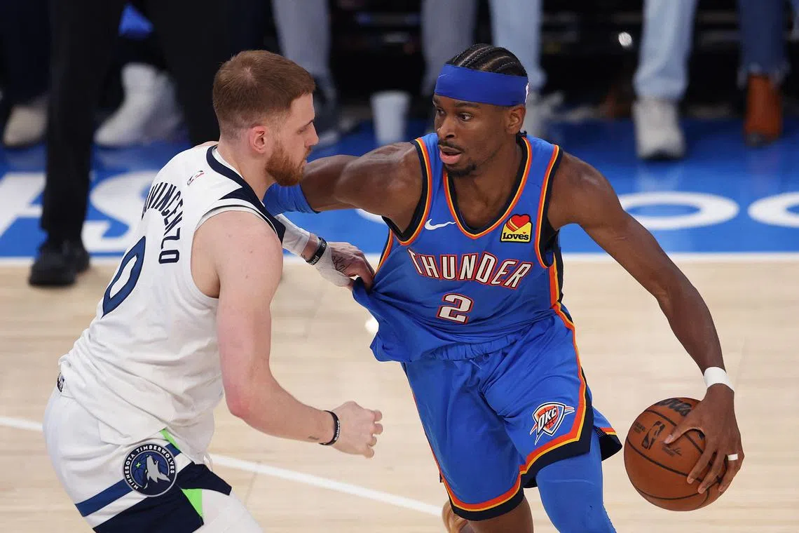 Shai Gilgeous-Alexander of the Oklahoma City Thunder dribbles the ball against Donte DiVincenzo of the Minnesota Timberwolves in the Western Conference Finals.