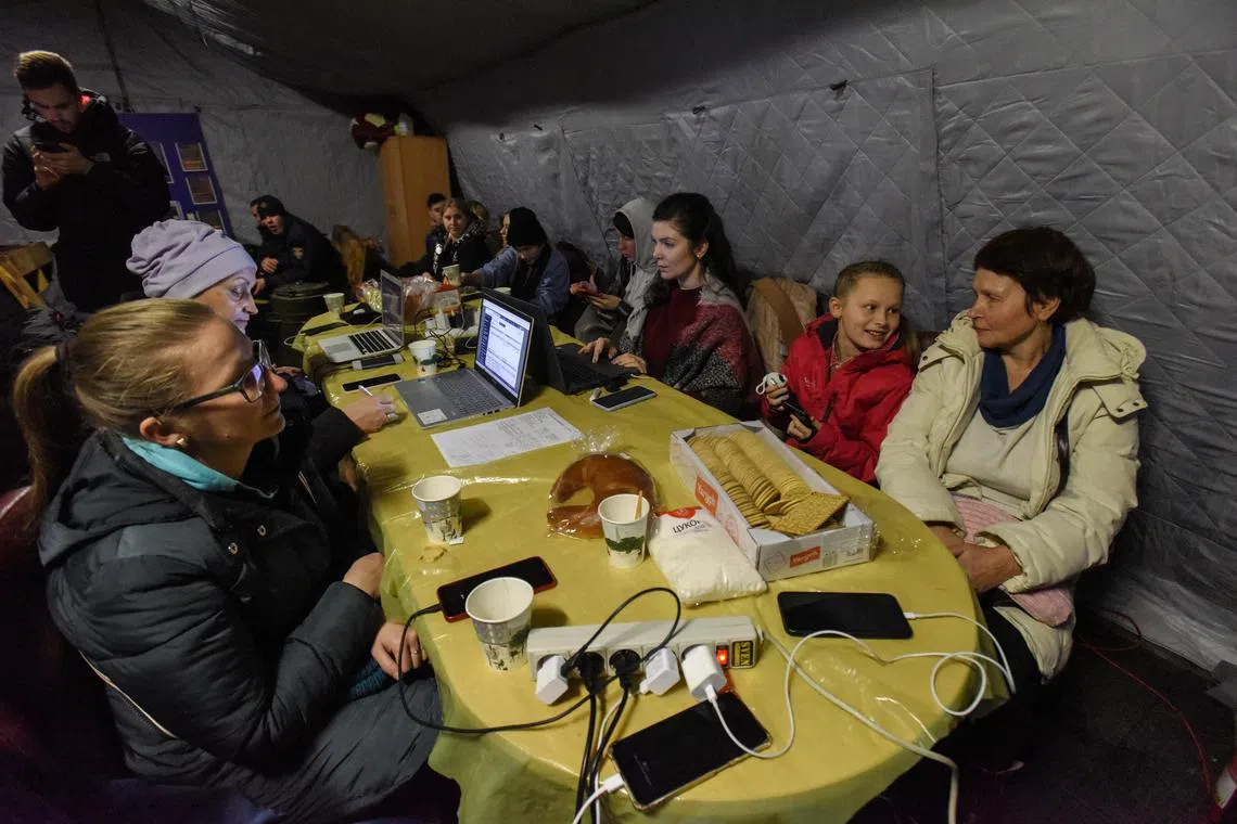People charging their devices from a power generator at a heating point during a power cut in Kyiv, Ukraine, on Dec 16, 2022.