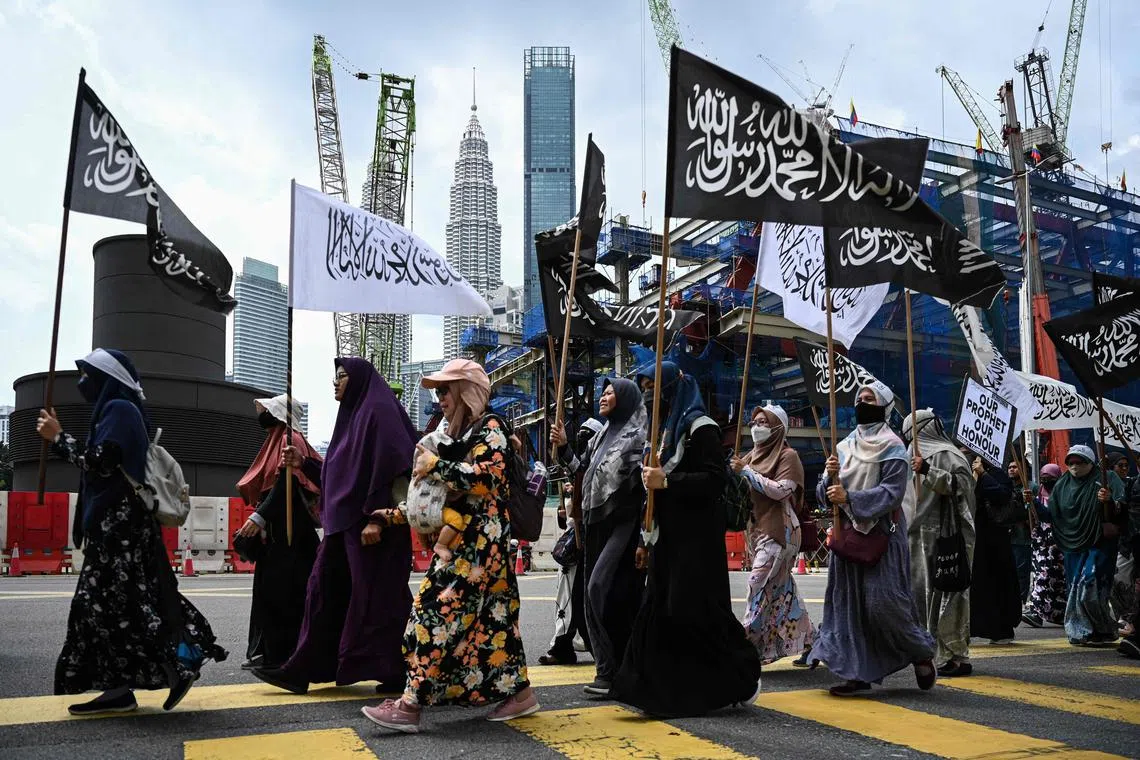 Malaysian Muslim women carry flags as they march toward the Netherlands embassy during a protest against Edwin Wagensveld, a Dutch far-right leader of an anti-Islam group who tore out pages of the Koran in The Hague, in Kuala Lumpur on January 27, 2023. - Protests have erupted across the Muslim world after Swedish-Danish far-right politician Rasmus Paludan set fire to a copy of the Koran in Stockholm, which was followed by Edwin Wagensveld, Dutch leader of anti-Islam group Pegida, tearing pages out of the Koran in The Hague. (Photo by Mohd RASFAN / AFP)