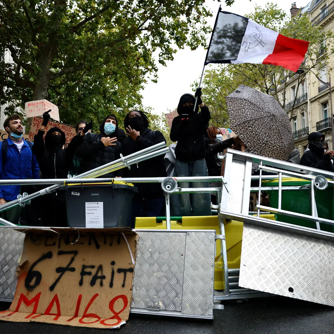 A protester holds a French flag behind a barricade to block the Boulevard Saint-Germain during a blockade of Sciences Po university in Paris as part of nationwide student protests demanding better school conditions, France, October 7, 2026. The slogan on the placard reads \"\"Generation Six - Seven re-enacts May 68\".  REUTERS/Sarah Meyssonnier