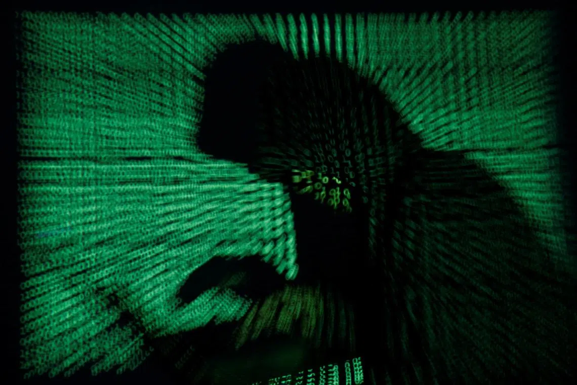 A hooded man holds a laptop computer as cyber code is projected on him in this illustration picture taken on May 13, 2017. REUTERS/Kacper Pempel/Illustration