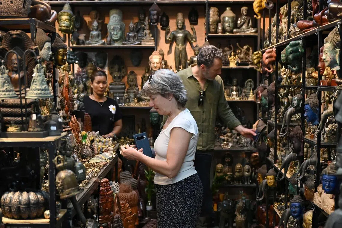 Tourists looking at sculptures at a souvenir shop in a market in Siem Reap province on Dec 18, 2025