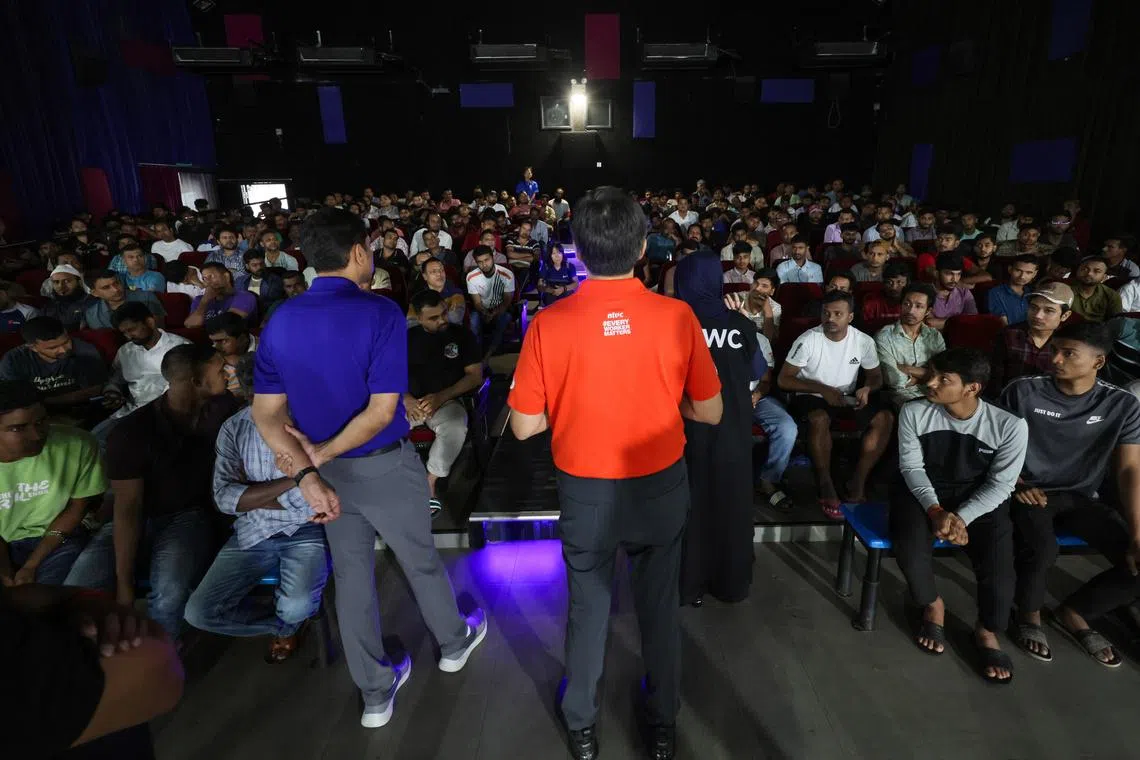 NTUC Secretary-General Ng Chee Meng (centre, in red) and Minister of State for the Ministry of Manpower Dinesh Vasu Dash (left, in blue) speaking to the migrant workers affected by the alleged unpaid wages involving KPA Engineering and SK Industries at Tuas View Dormitory on June 24.