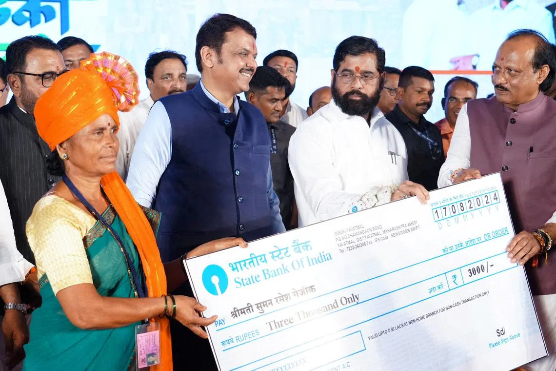 FILE PHOTO: Maharashtra Chief Minister Eknath Shinde accompanied by his deputies Devendra Fadnavis and Ajit Pawar hands a symbolic cheque to a beneficiary of a government welfare scheme, in Kinhi, Maharshtra, India August 24, 2024.   Devendra Fadnavis via X/Handout via REUTERS/File Photo