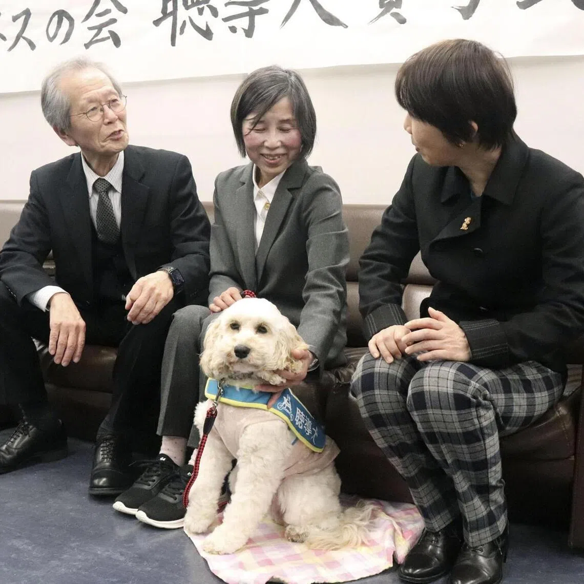 Mieko Tsurumura (middle) with hearing assistance dog Grace at the Hiroshima prefectural government office in Hiroshima on March 25. 